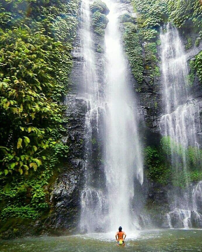 Traveller standing below Sekumpul Waterfall in Bali